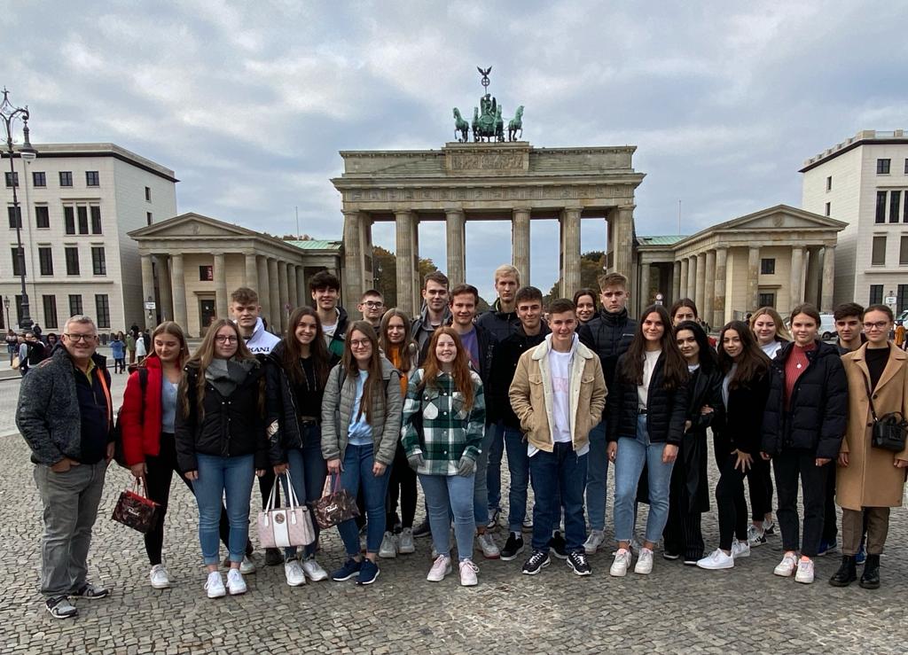 Schülergruppe vor Brandenburger Tor, darüber Wolken und Dämmerlicht
